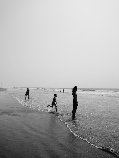 Free Silhouetted figures on a serene beach in Goa, India during the day. Stock Photo