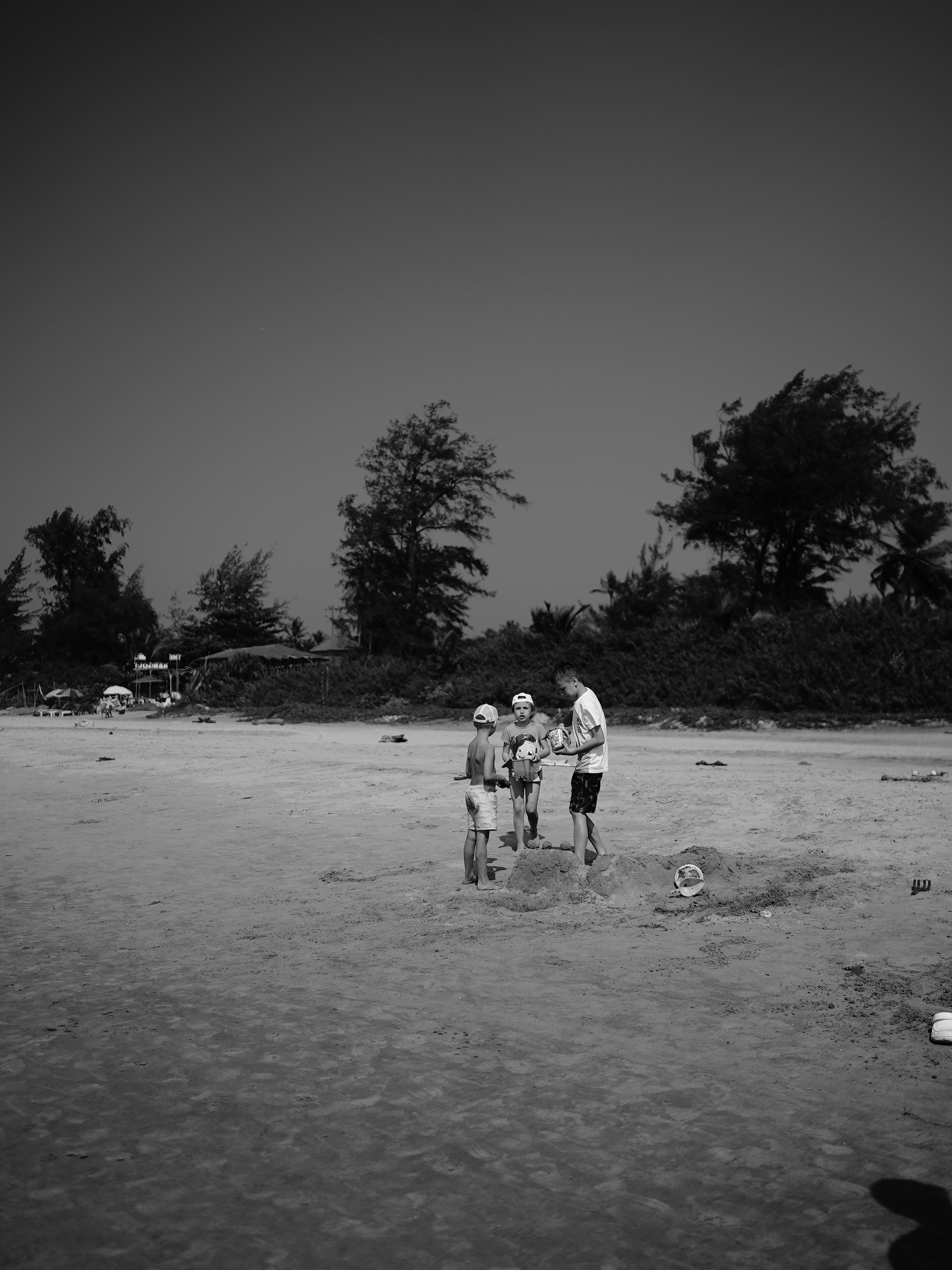 Black and white image of a family enjoying a sunny day on a Goa beach.