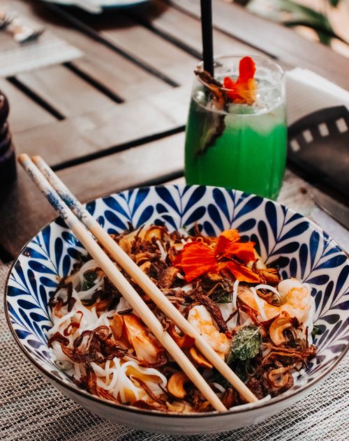 Free Colorful noodle dish paired with a refreshing green cocktail, set outdoors in Nairobi, Kenya. Stock Photo