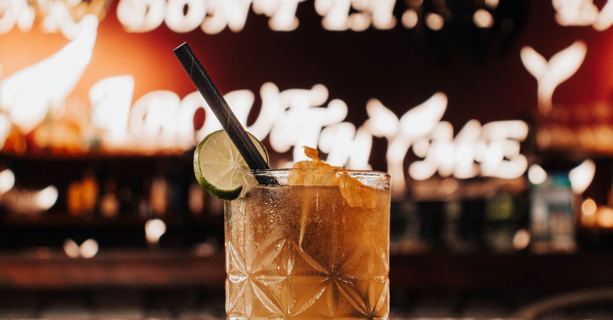 A classic cocktail on a bar counter with lime garnish, creating a moody evening vibe.