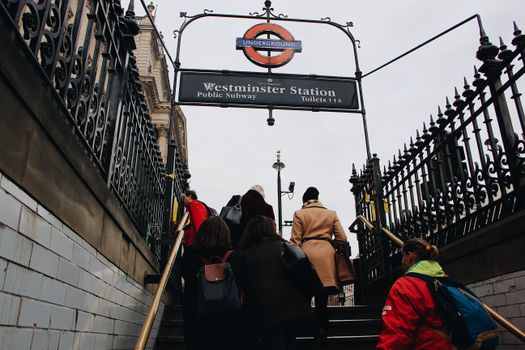 Low angle of anonymous people walking up stairs while leaving subway station on gray day in city