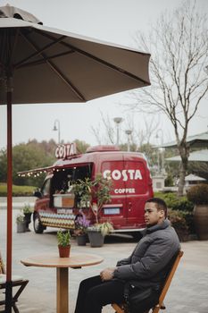 Relaxing moment at an outdoor cafe with a coffee van in view, capturing a cozy atmosphere.