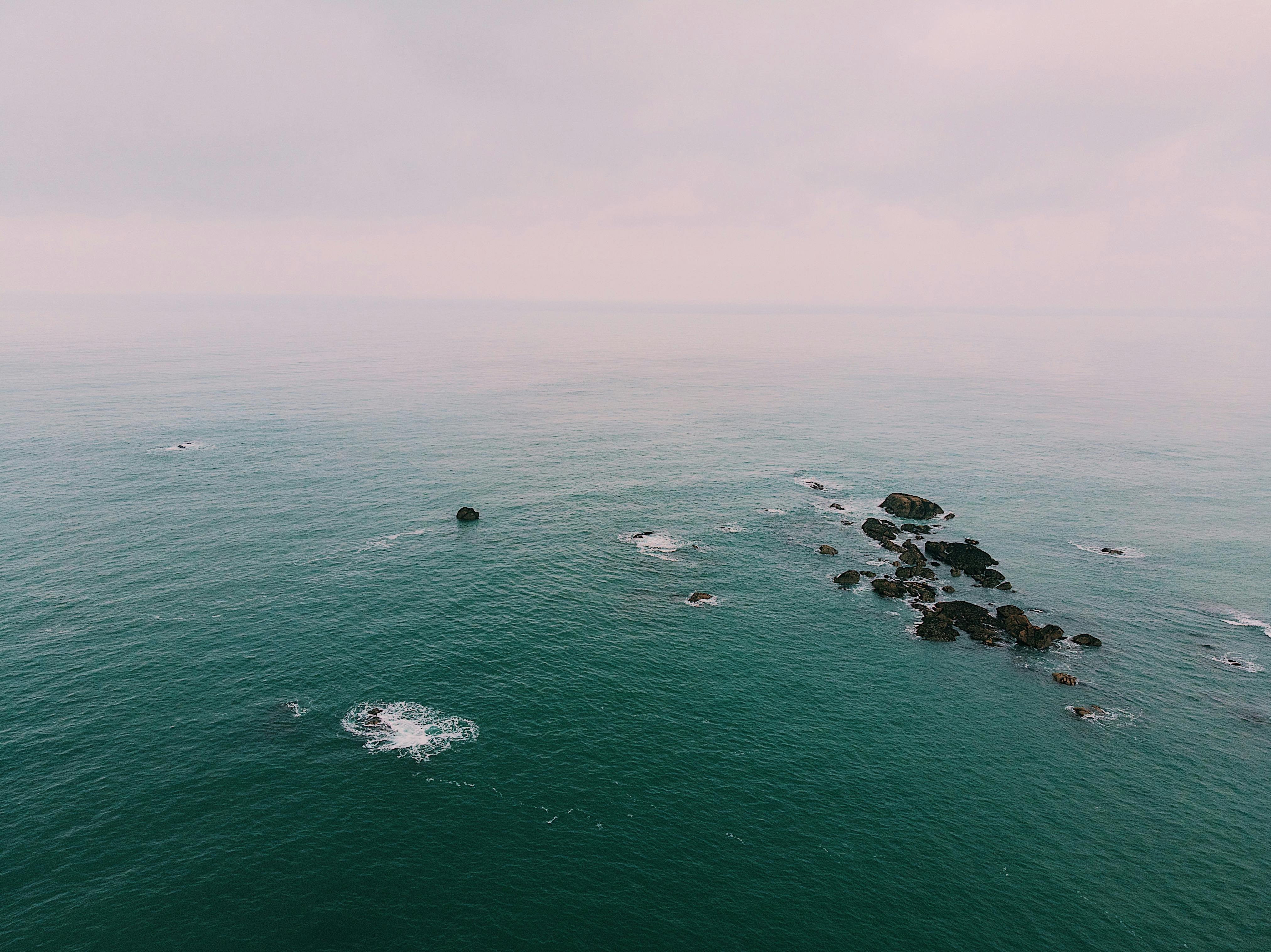 从空中俯瞰，多云天空下宁静的海洋中散布着岩石结构