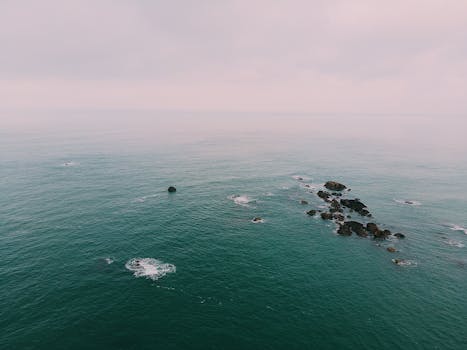 从空中俯瞰，多云天空下宁静的海洋中散布着岩石结构