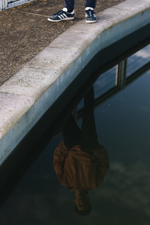 Reflection Photo of Person Standing on Poolside