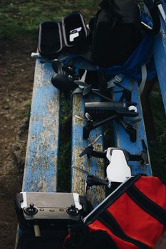 A variety of drones and controllers arranged on a rustic blue bench, ready for an outdoor flight.