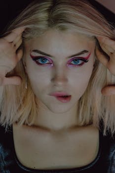 A dramatic portrait highlighting a woman's bold makeup and intense gaze.