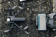 Top view of modern drone and controller with smartphone placed on rough ground before flight
