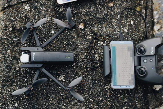 Top view of modern drone and controller with smartphone placed on rough ground before flight