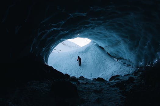 A lone adventurer walks inside an icy cave, surrounded by snowy terrain and winter scenery.