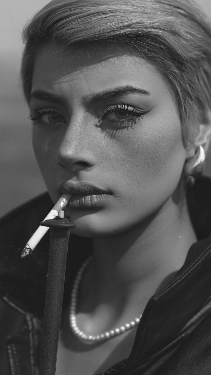 Black and white portrait of a stylish woman with short hair and a cigarette, showcasing attitude.