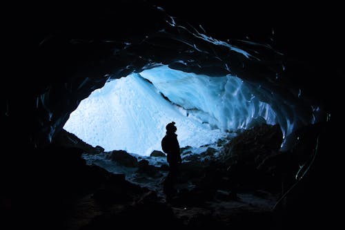 Silhouette Photo of Person Standing in Cave