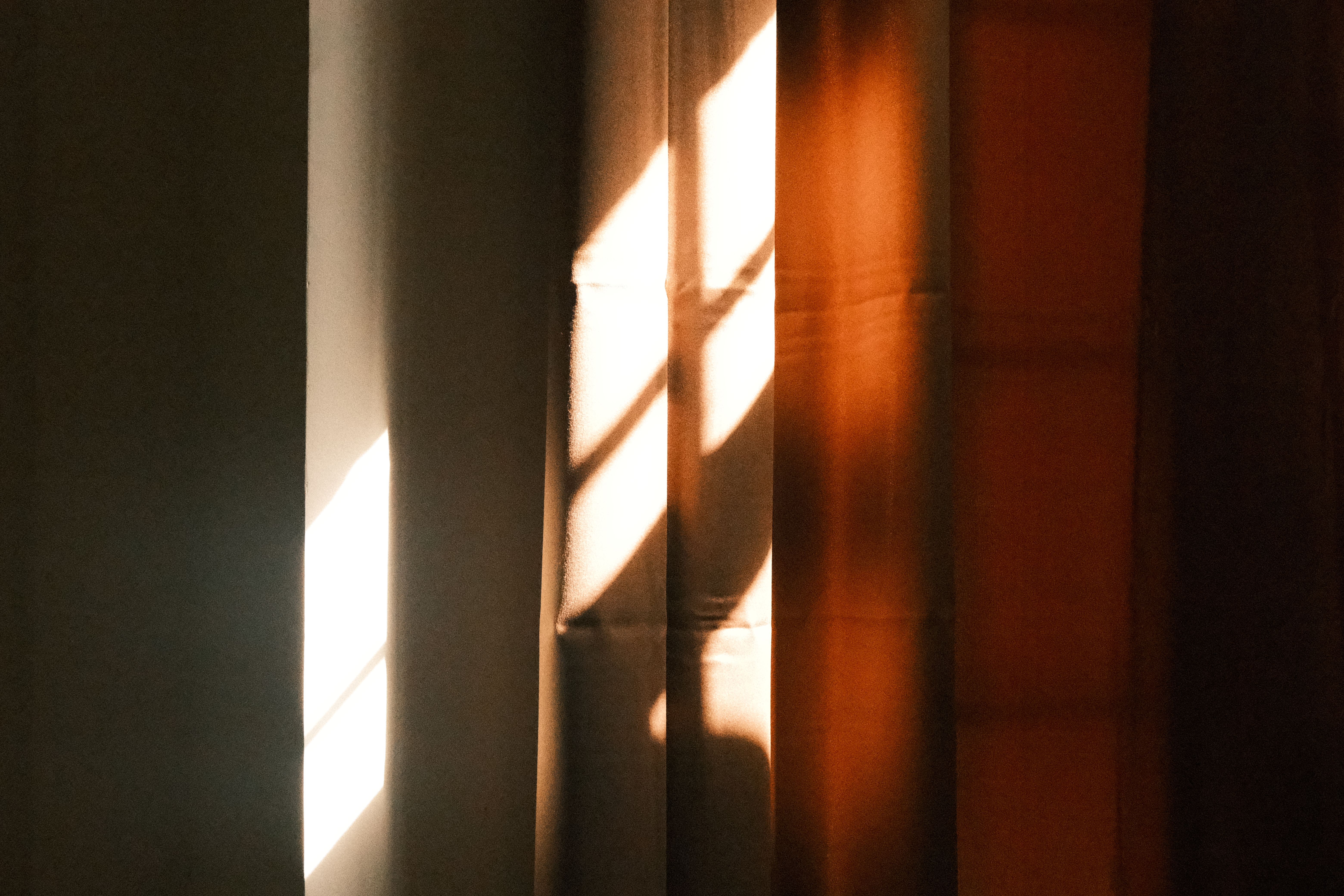 Kostenlos Sonnenbeschienene Muster erzeugen in dieser künstlerischen Fotografie eine warme Atmosphäre auf strukturierten Vorhängen. Stock-Foto