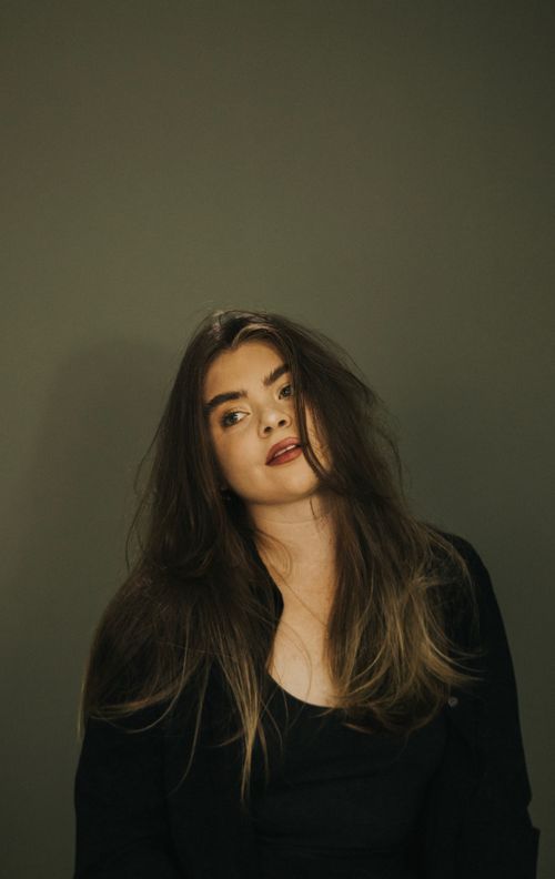 Free Stylish portrait of a young woman with flowing hair against a neutral background. Stock Photo