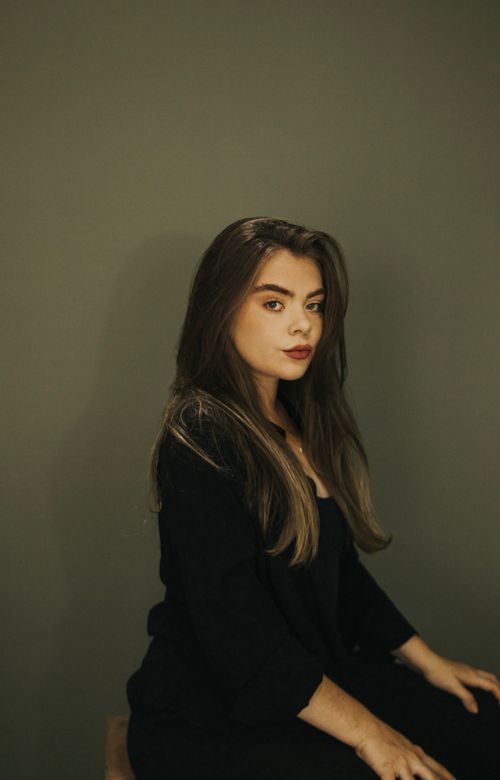 Free Sophisticated portrait of a young woman in a black outfit against a neutral background. Stock Photo