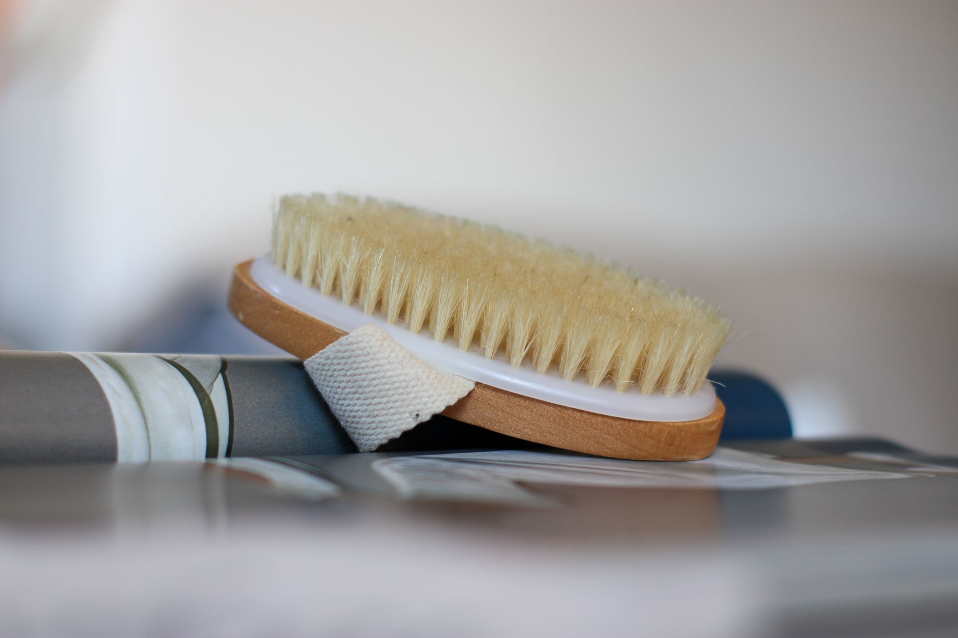 10 Best Skin Care Hacks For Glowing Skin 1 A close-up of a natural bristle body brush resting on a soft surface with a strap for easy handling.