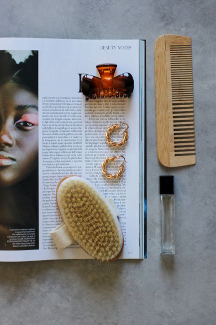 Beauty and hair accessories arranged on a fashion magazine page, top view.