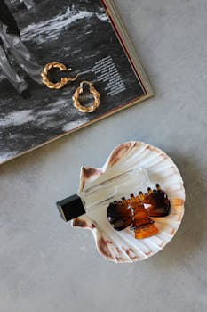 Flat lay of a perfume bottle, shell, and accessories for a stylish, minimalist look.
