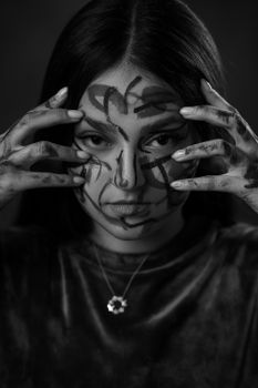 Black and white portrait of a woman with abstract face paint, conveying mystery.