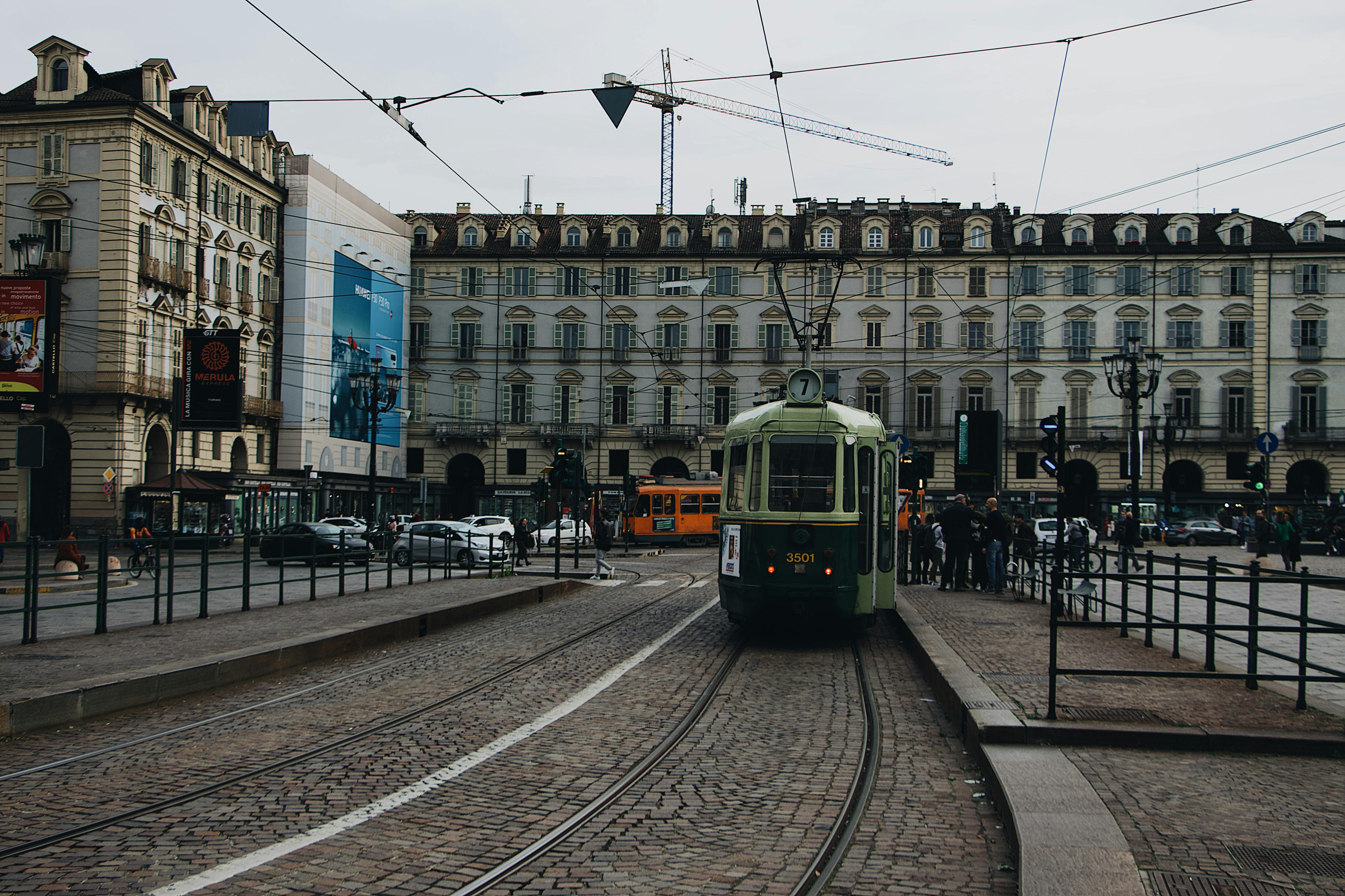 A vintage tram navigating through a bustling European city square with historic architecture.