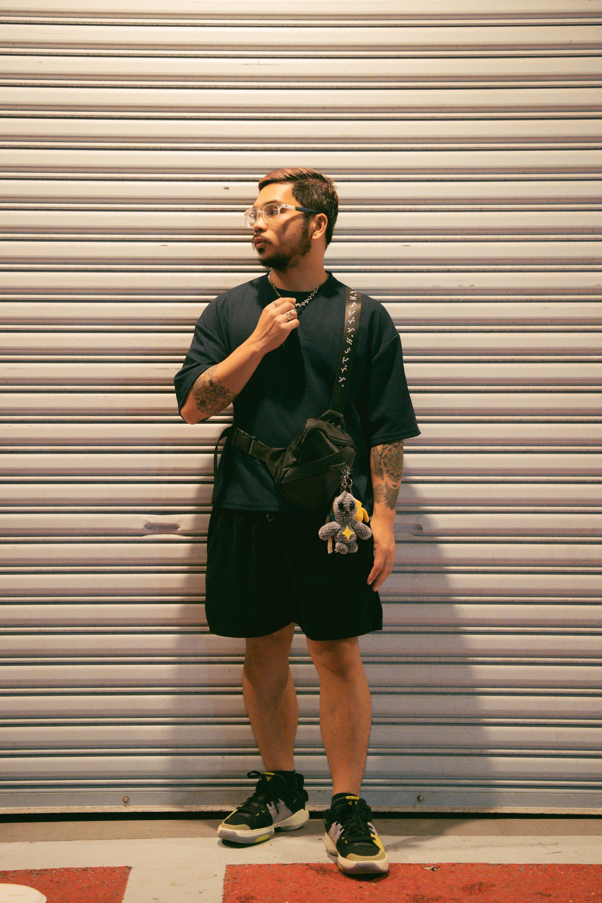 Stylish adult in urban setting wearing casual fashion with accessories.