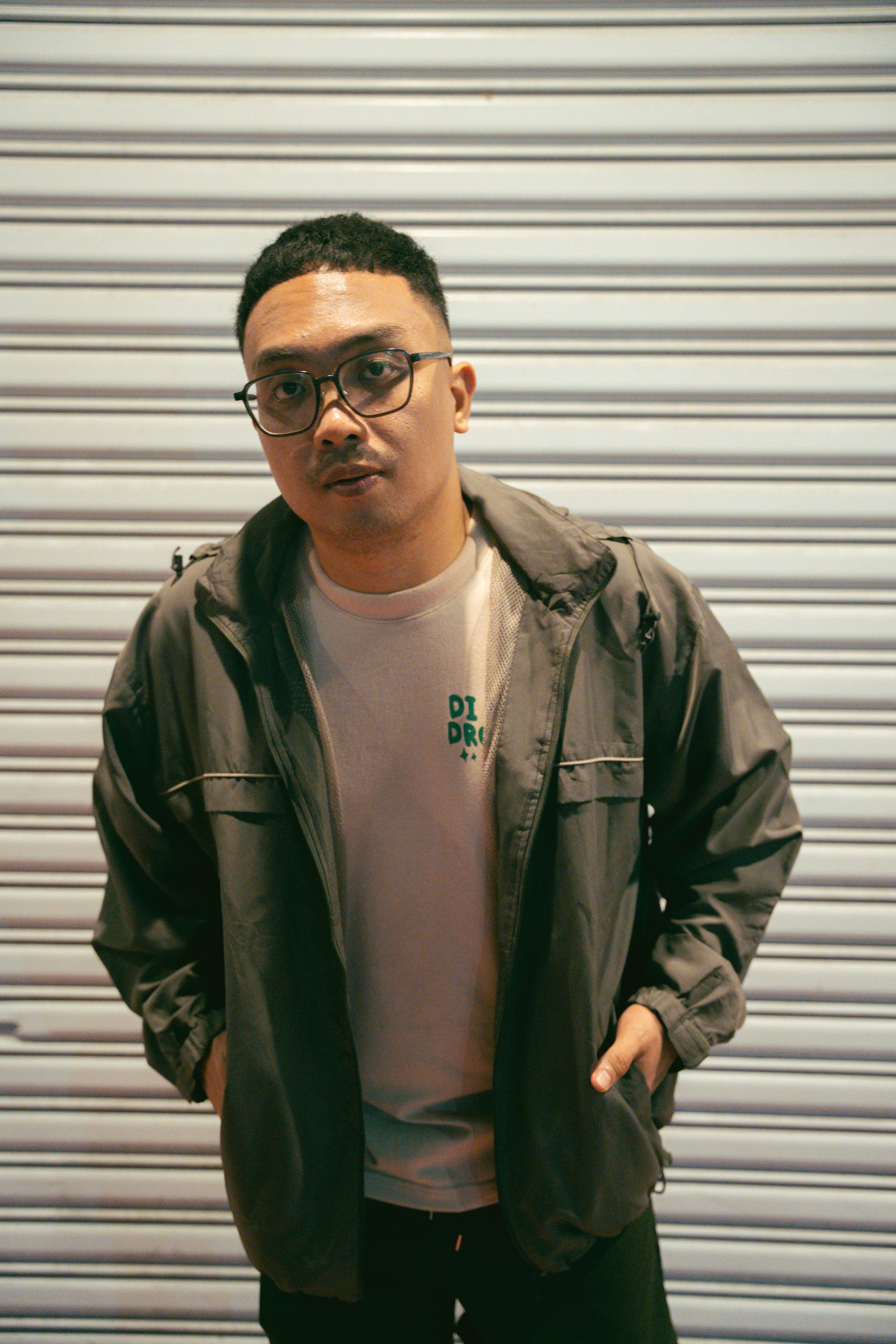 Urban portrait of a young man in casual attire against a shutter background.