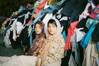 在一家纺织店里，两名妇女坐在鲜艳的衣服中间