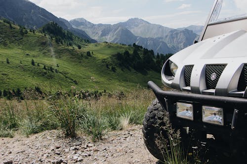 Scenic View Of Lush Green Mountains With A Vehicle Parked On A Unpaved Pathway