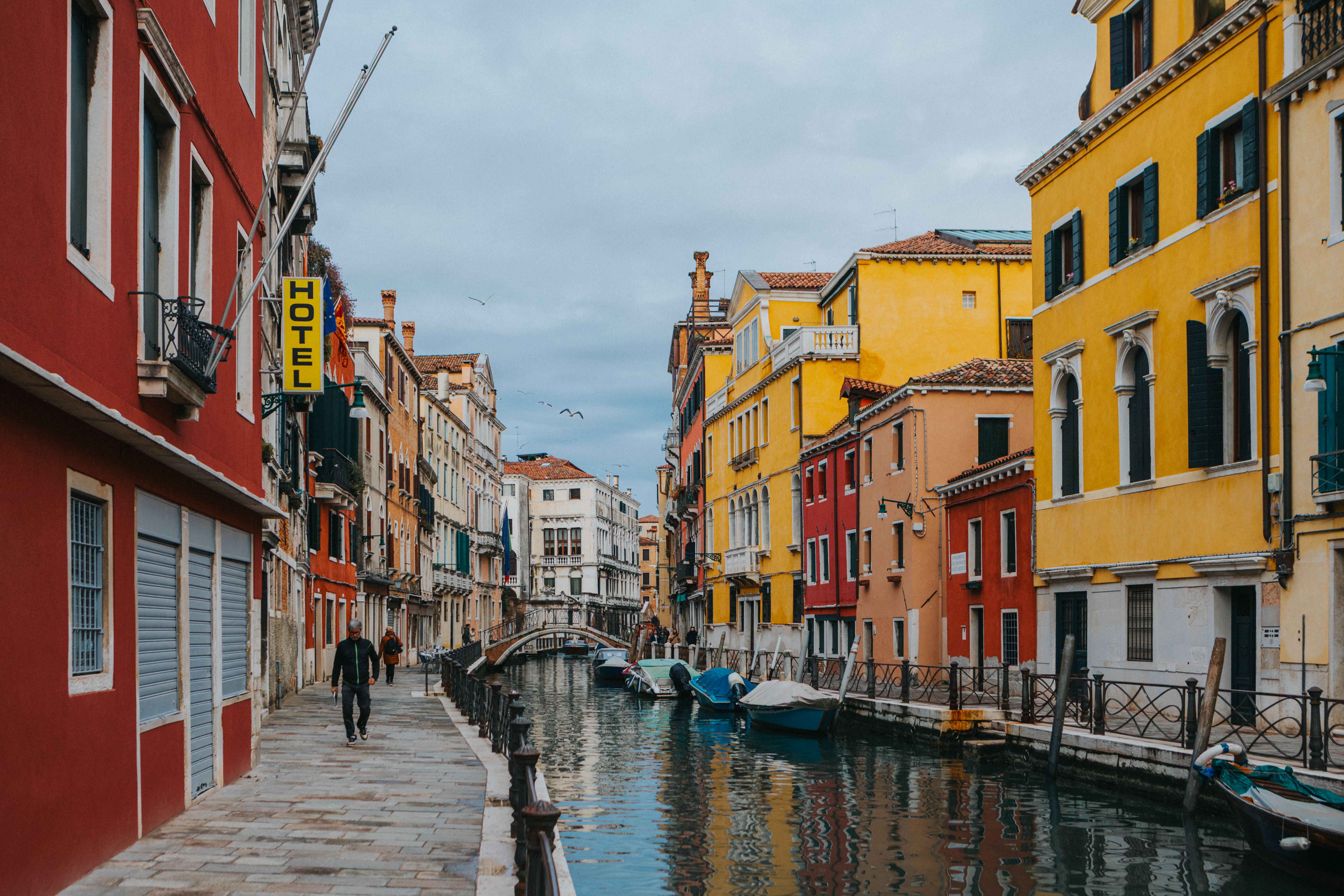 Pareja de turistas latinoamericanos revisando su itinerario y seguro de viaje frente a un canal en Venecia
