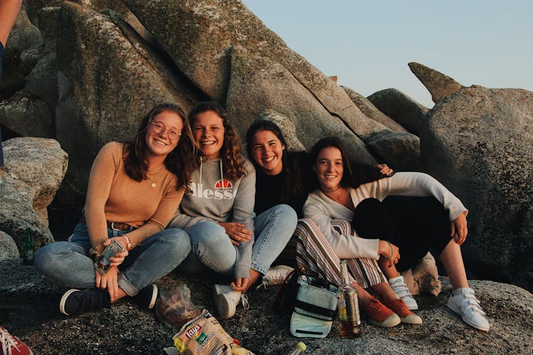 Happy Friends Resting On Rocky Coast