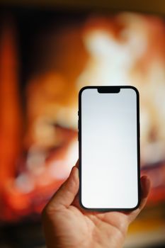 A smartphone held in front of a blurred fireplace, ideal for mockups.