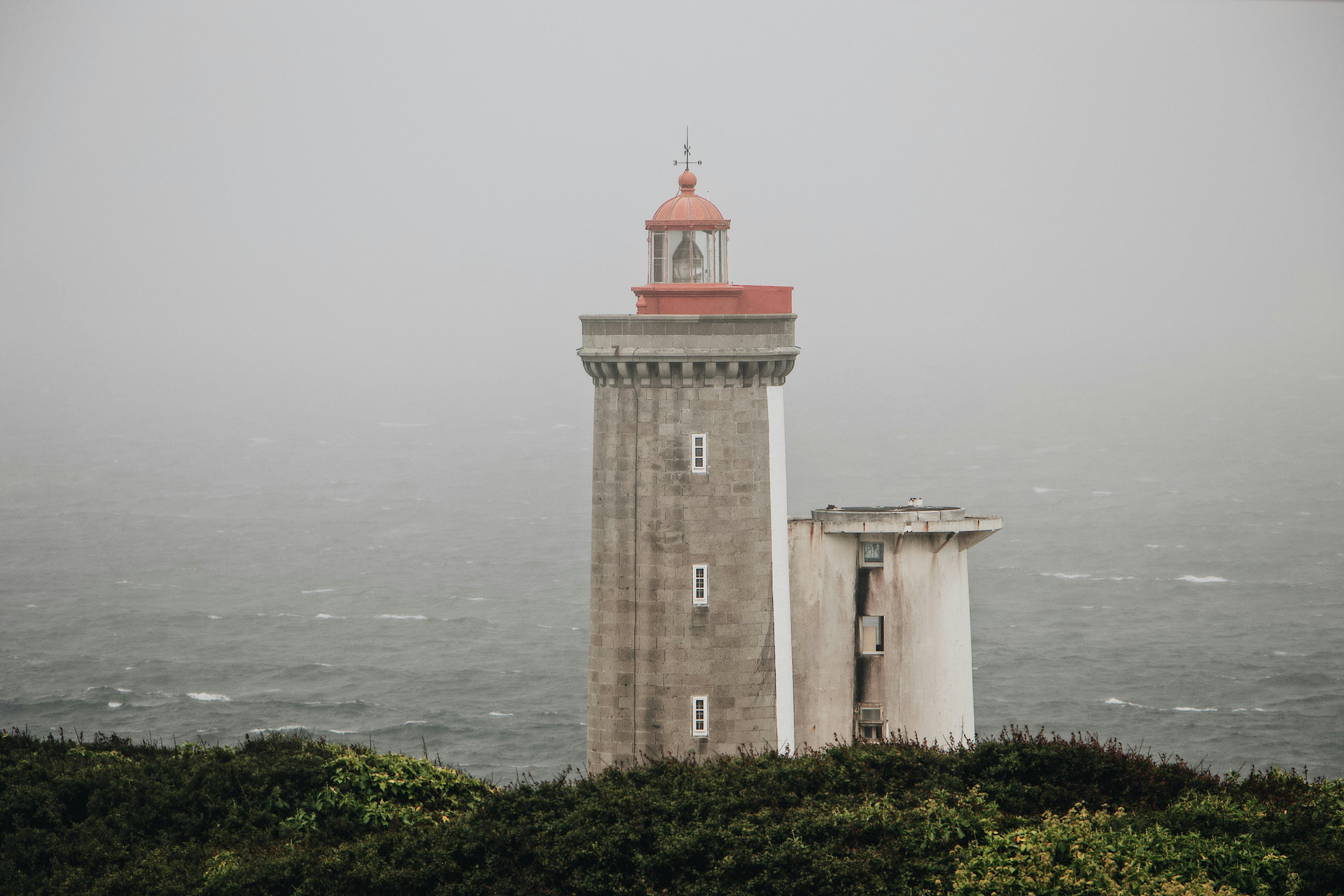 lighthouse on hill against gray sea