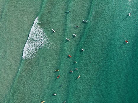 阳光明媚的日子里，冲浪者享受碧绿大海的航拍照片，非常适合旅行和休闲主题