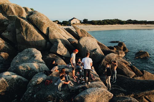 Un Grupo De Jóvenes Holgazaneando Alrededor De Las Rocas Junto Al Mar Cerca De La Costa