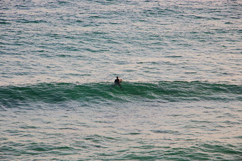 A lone surfer waits amidst the ocean waves, envisioning the perfect surf opportunity.