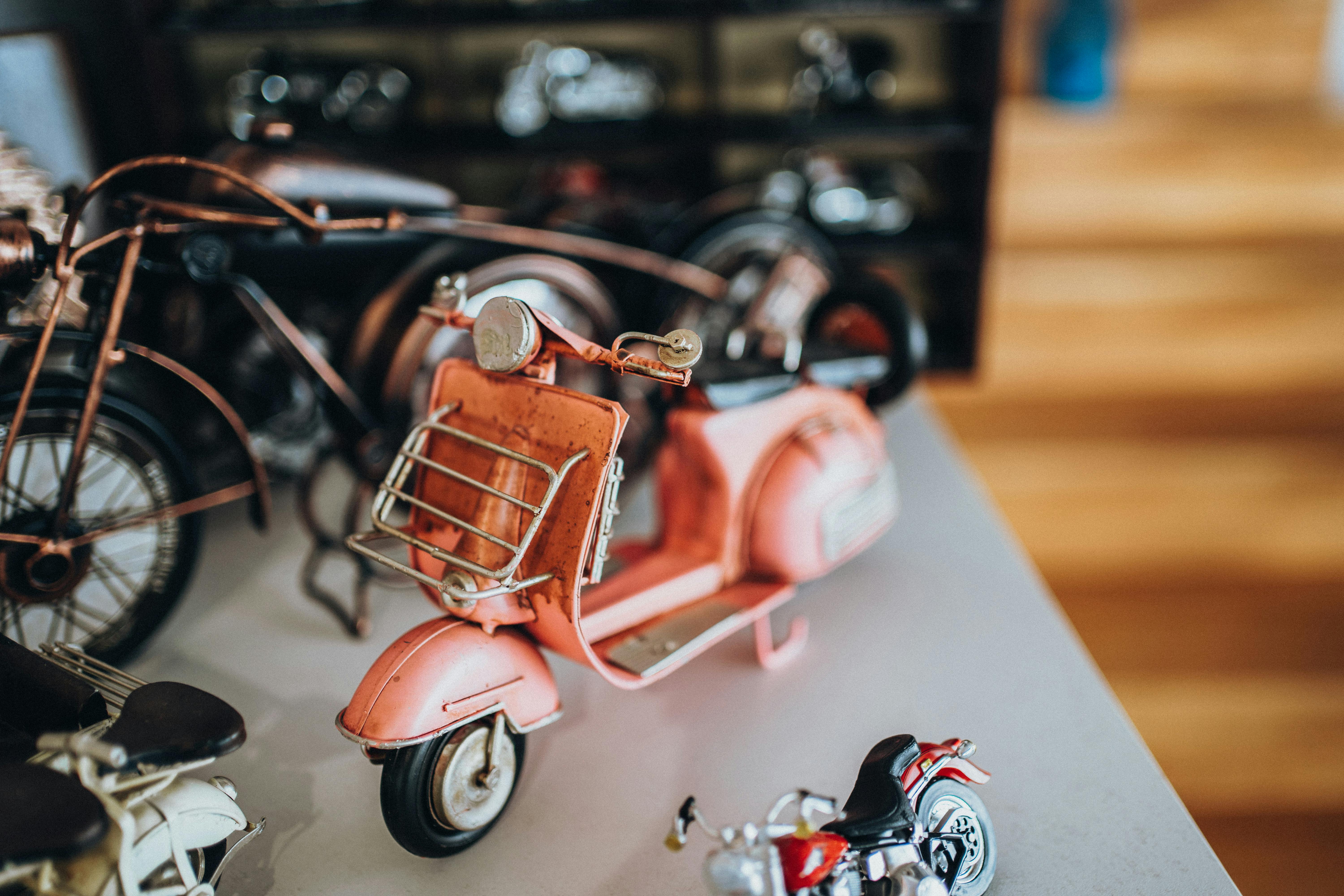 Close-up of vintage toy motorcycles on display with a focus on a pink scooter.