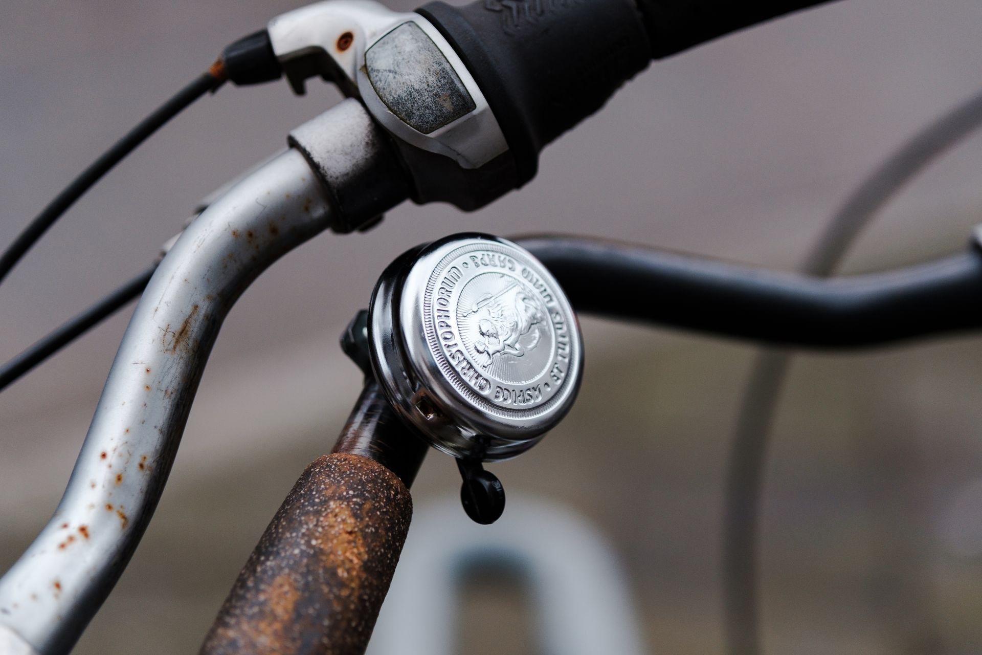 Detailed view of a vintage bicycle handlebar and bell with rust and chrome finish.