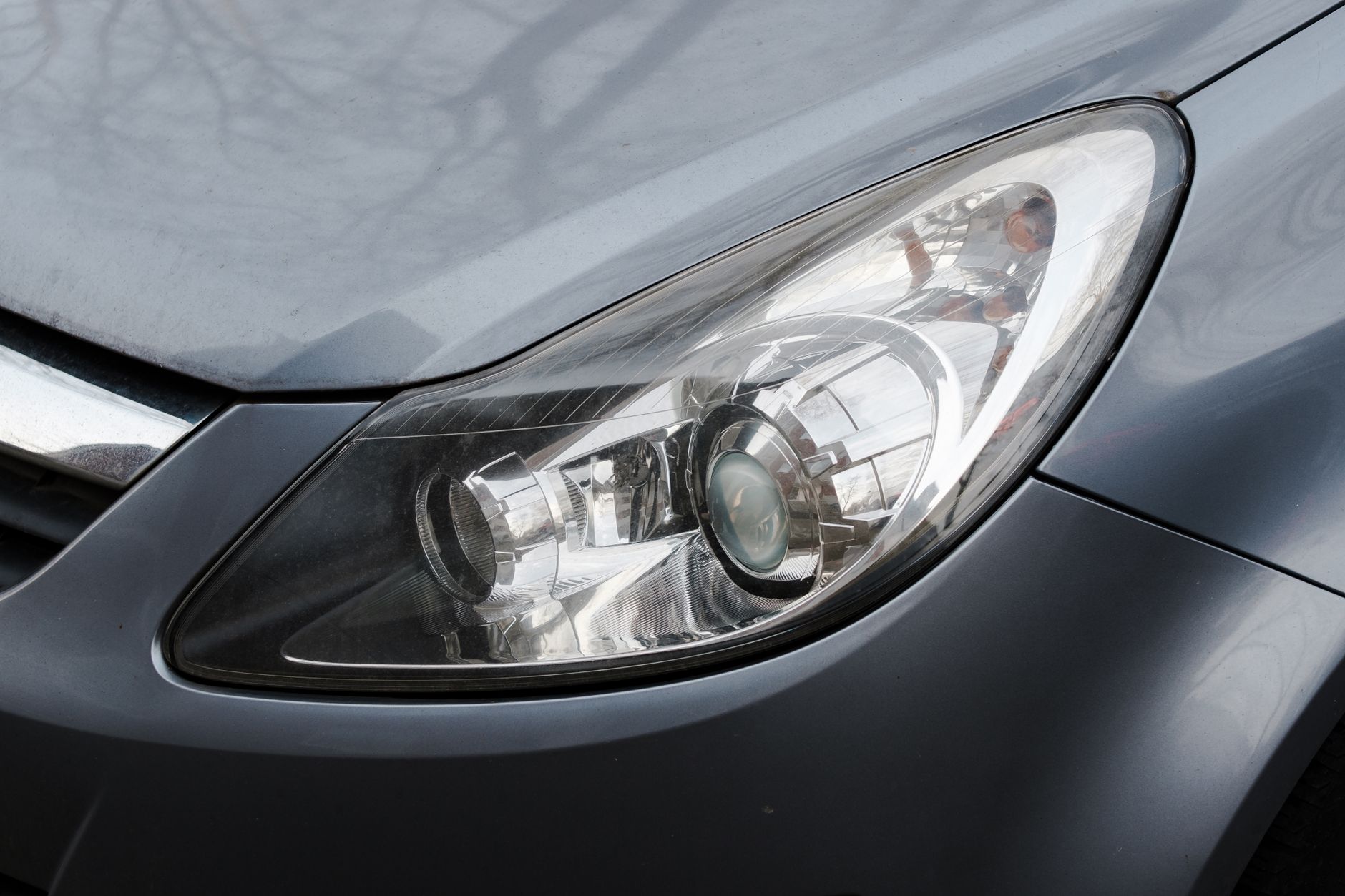 Detailed close-up of a shiny modern car headlight with metallic finish.
