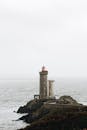 一座孤独的灯塔矗立在岩石海岸上，俯瞰着薄雾而宁静的海洋