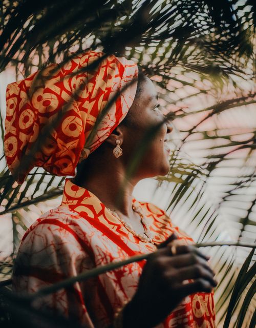Free Woman in vibrant traditional attire smiling among palm fronds, evoking a sense of joy and cultural richness. Stock Photo