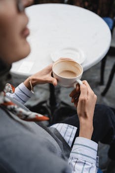 Close-up of a person enjoying a coffee at an outdoor cafe, creating a sense of relaxation.