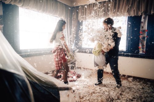 Free A playful indoor pillow fight between two adults, feathers flying everywhere. Stock Photo