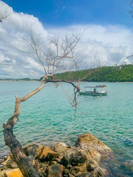 Stunning view of Unawatuna Beach in Sri Lanka showcasing a calm turquoise sea, boat, and unique rock formations under a sunny sky.