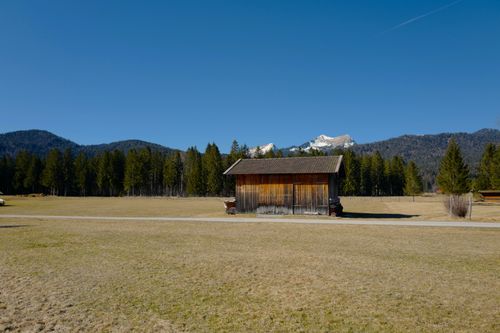 Free A peaceful scene featuring a rustic barn set against a backdrop of mountains and trees. Stock Photo