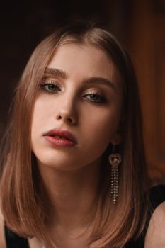Close-up portrait of a young woman with stylish earrings and natural makeup.