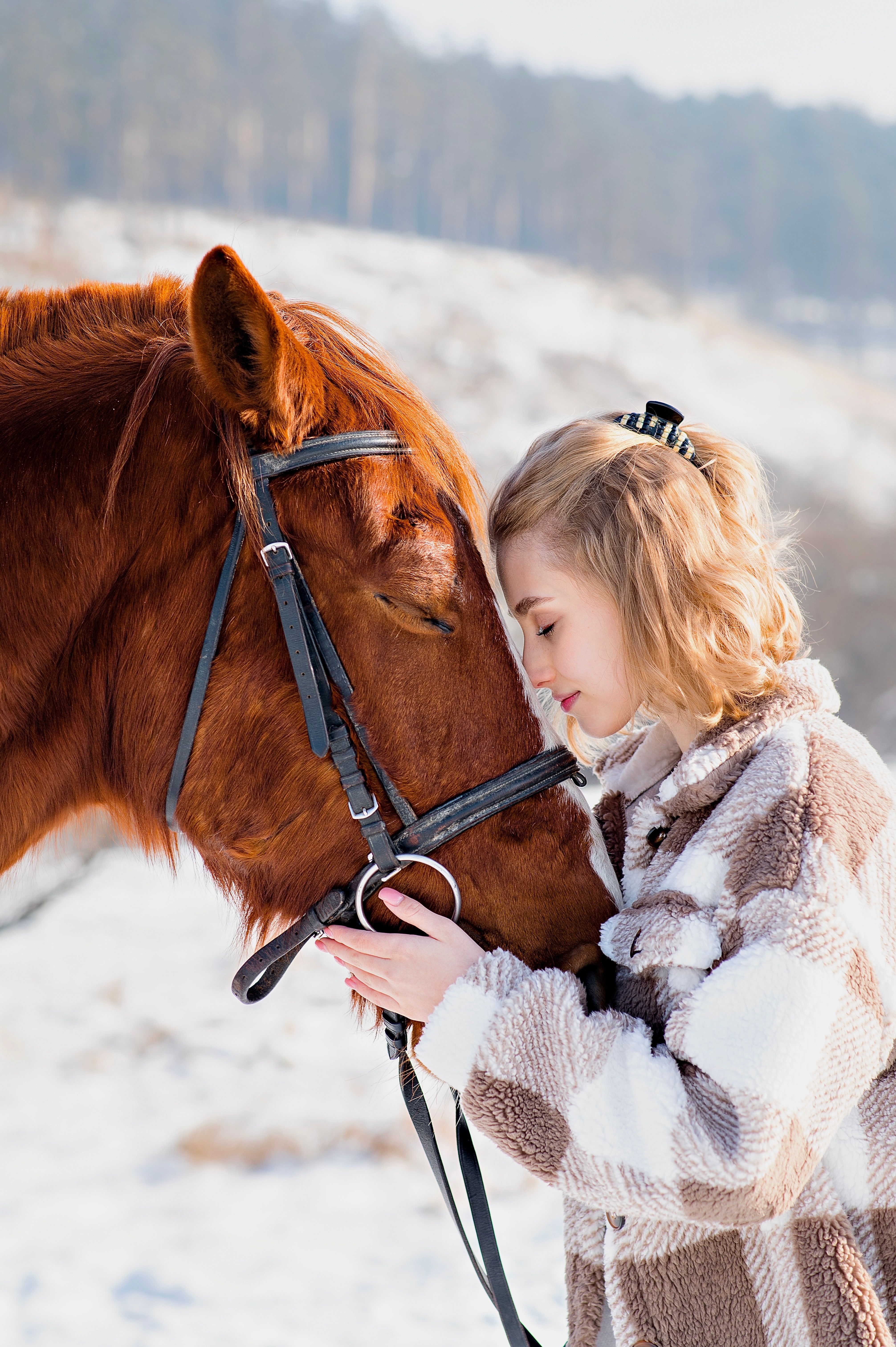 Serene interaction between a woman and a horse in a snowy winter landscape.
