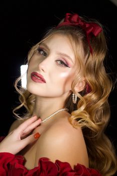 Stunning portrait of a woman with curled hair, red bow, and pearl jewelry.