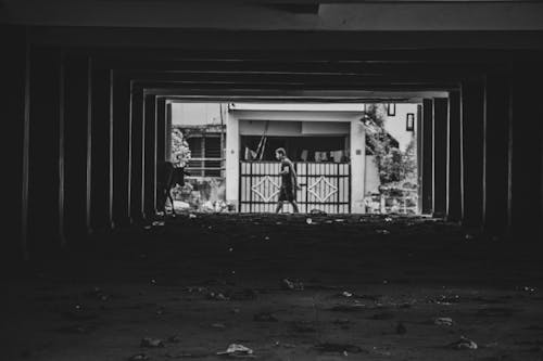 Fotografi Grayscale Manusia Berjalan Di Samping Gerbang