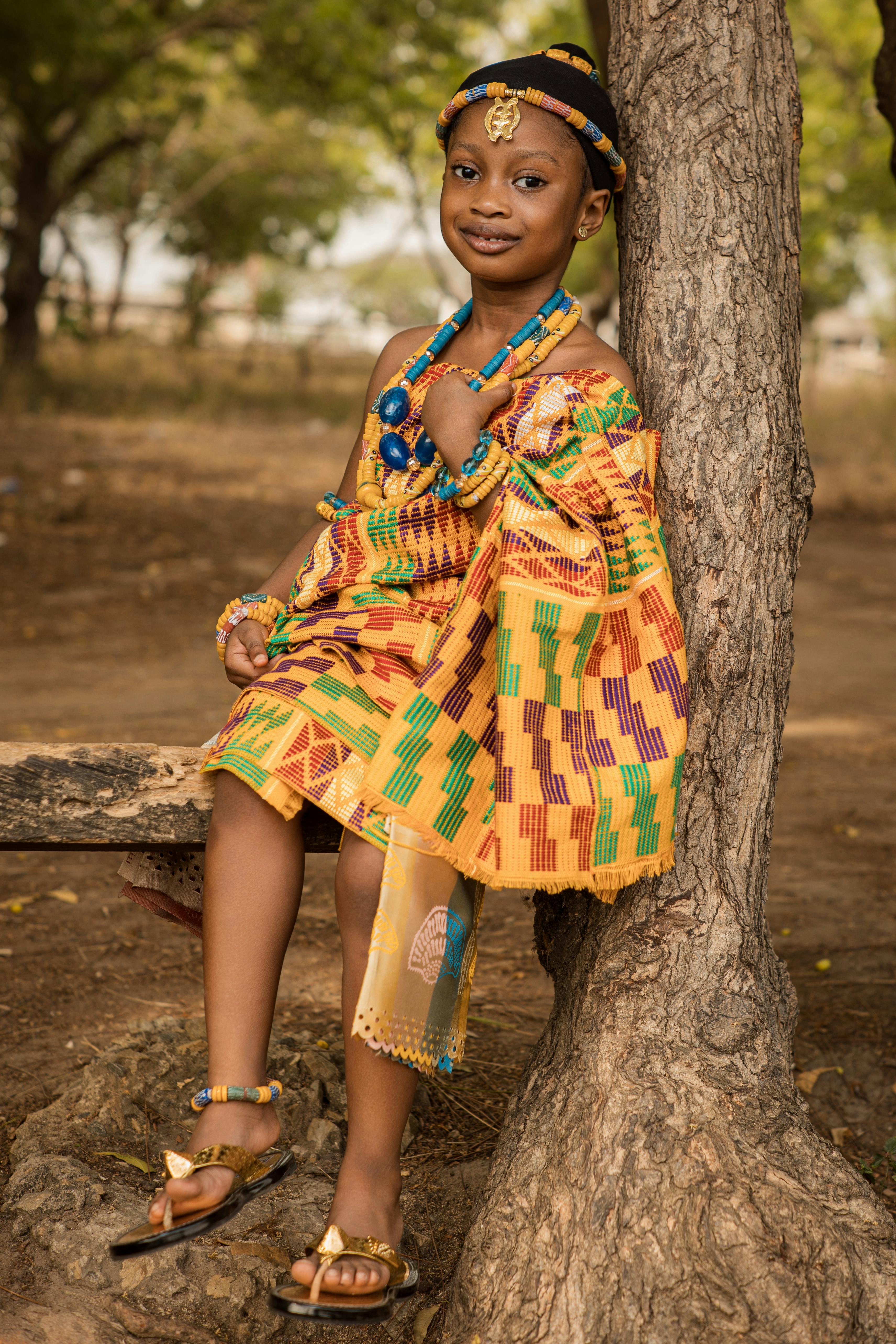 De franc Un nen amb un drap Kente vibrant posa amb confiança en un entorn natural. Foto d'estoc