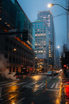 Street view of downtown Seattle at night with illuminated skyscrapers and wet roads.